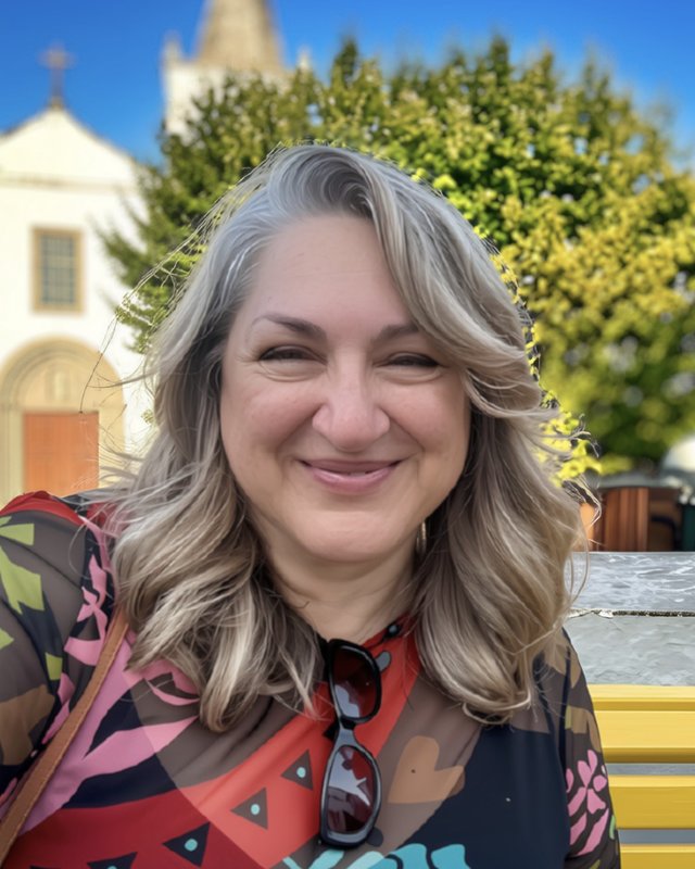 Elsa Patrício de Barros smiling on a yellow bench in front of a white church in Portugal